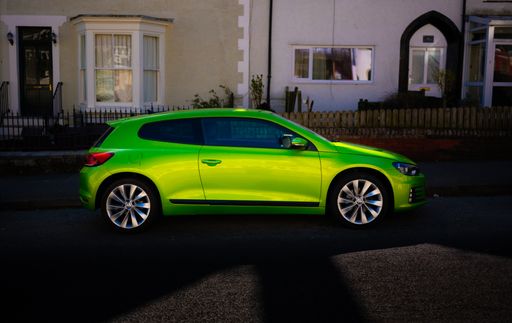 A closeup shot of a bright green Volkswagen Scirocco car parked in front of a building, Wigan, United Kingdom