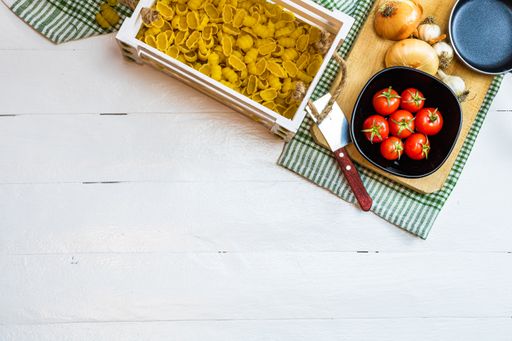 A top view of an Italian pasta ingredients on a white table with copyspace