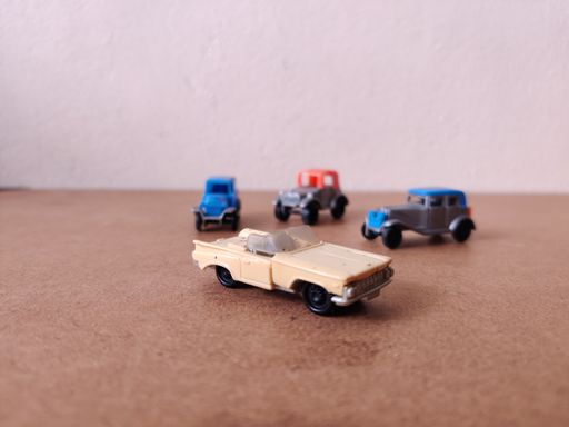 A light yellow classic ford thunderbird toy car with toy cars in the background