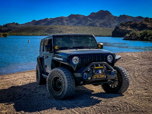 A black Jeep Wrangler off-roading on Arizona trails near a lake