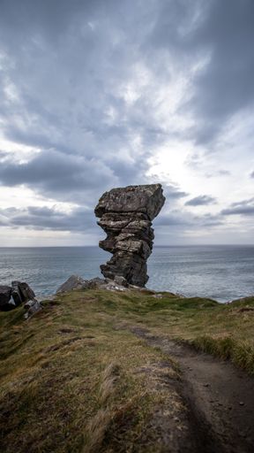 A beautiful landscape of a pile of stones on green cliff near the ocean on the sunrise