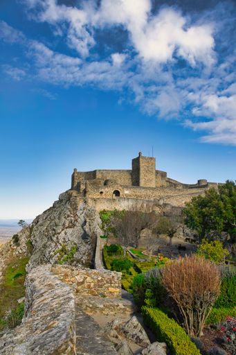 A vertical shot of the Castle of Marvao on a mountain surrounded by greenery on a clear day