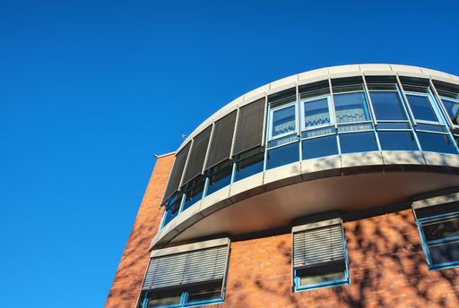 A low angle shot of an orange building with modern windows under the clear skies