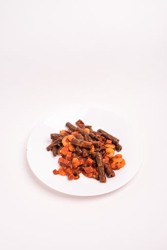 A vertical high angle shot of cooked black penne pasta with shrimp on a white plate isolated on a white background