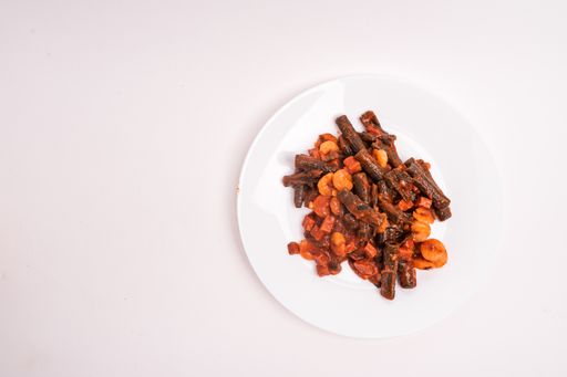 A high angle shot of cooked black penne pasta with shrimp on a white plate isolated on a white background