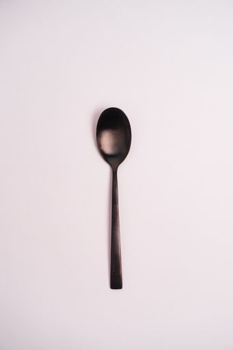 A vertical shot of a spoon isolated on a light-colored background