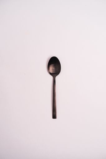 A closeup shot of a metal teaspoon isolated on a light-colored background