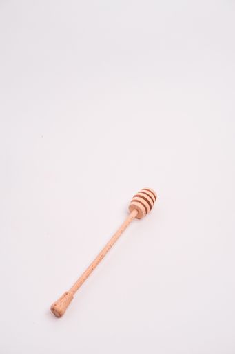 A closeup shot of a honey dipper isolated on a light-colored background