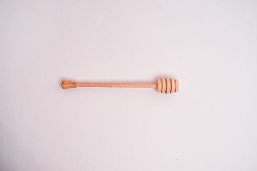 A closeup shot of a honey dipper isolated on a light-colored background
