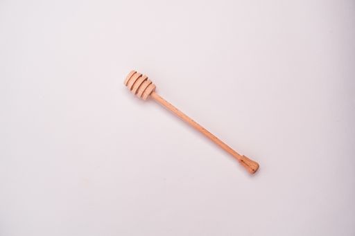 A closeup shot of a honey dipper isolated on a light-colored background