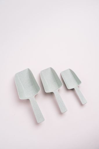 A closeup shot of three white food shovels isolated on a light-colored background