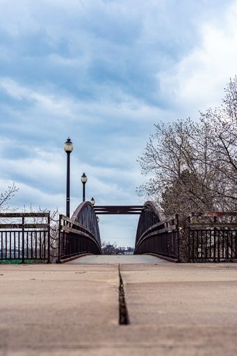 A vertical shot of a rusty old iron walkway bridge on the train tracks