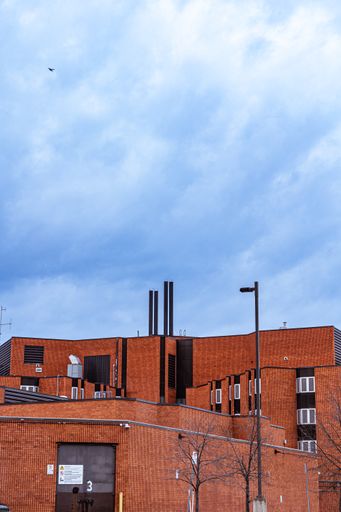 A vertical shot of a red building with chimneys on a cloudy day in Hamilton