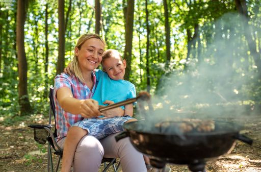 A happy mother and son making barbecue in the nature