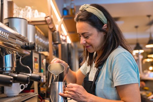 A smiling waitress preparing coffee in a coffee machine in the cafeteria