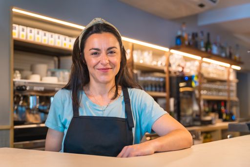 A smiling waitress with a coffee machine in the background