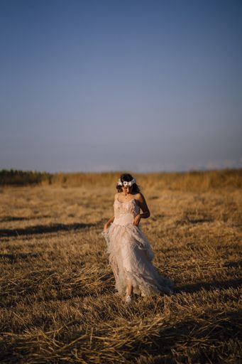 A vertical shot of a young caucasian female in white dress and white flower wreath posing in a field
