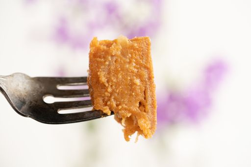 An orange toned sweet potato pie slice on an antique silver fork