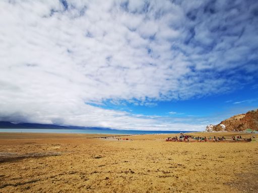 A scenic view of shore of the holy lake Namtso under the blue sky with fluffy clouds, Tibet