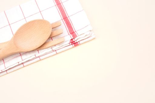 top view of wood spoon and fork with table napkin on a beige background with space for text
