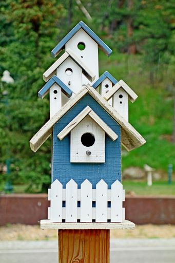 A vertical closeup shot of a beautiful blue and white wooden birdhouse with many roofs