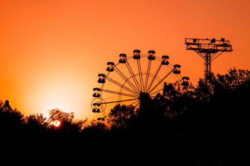 The silhouette of the Ferris wheel against the bright orange sky at sunset.