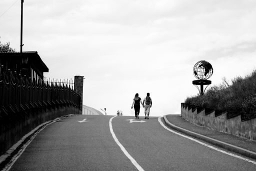 A grayscale shot of a young couple walking along the road. Gyumri, Armenia.