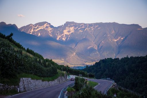 A wide shot of a highway going through a cliffy area with huge mountains in the background