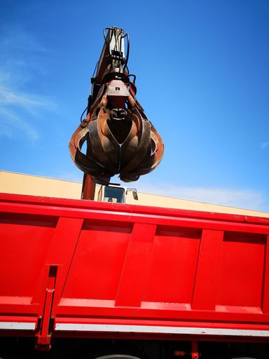 A low angle shot of a crane on top of a red truck with a blue sky in the background