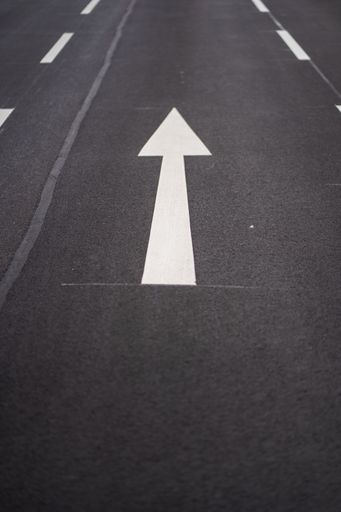 A high angle shot of white arrow road signs on the asphalt ground