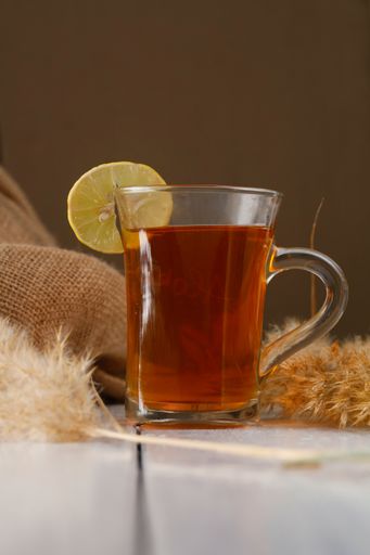 A closeup of a glass of hot tea on a white painted wooden surface