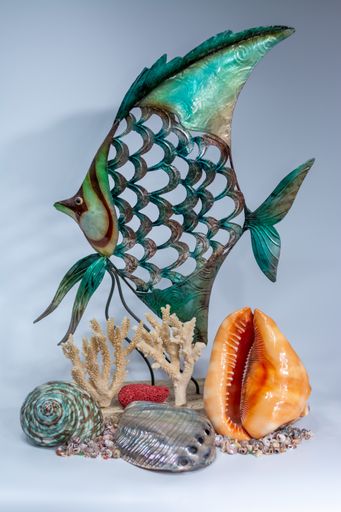 A vertical shot of a fish figurine with different seashells under it on a white surface and background