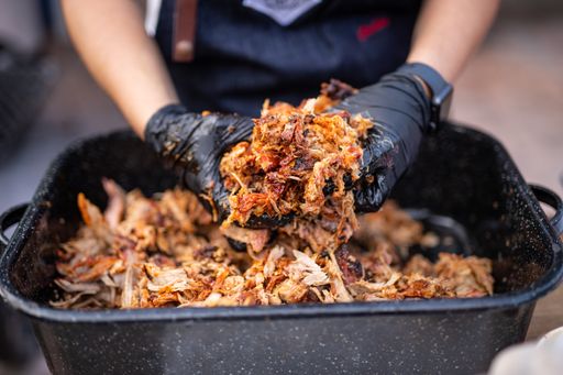 A chef's hands mixing meat with sauce in a black