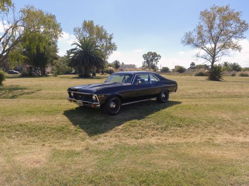Old black sporty Chevrolet Chevy Nova 250 SS coupe 1970s built by GM in the countryside. Nature grass and trees background. Classic car show