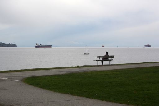 A woman sitting on the bench and looking into the ocean in Stanley Park, British Columbia, Canada