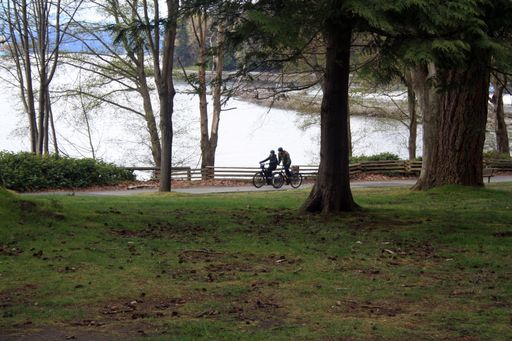 A couple of young people riding bicycles in Stanley Park, Vancouver, British Columbia, Canada