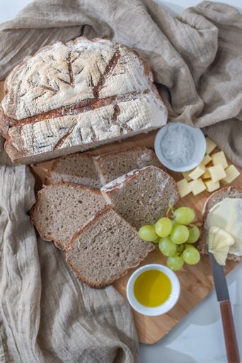 The sliced fresh crispy whole grain flour homemade bread with cheese and grapes on a cutting board