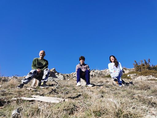 A happy family sitting enjoying nature in a sunny day on a hill with a blue sky on the background