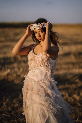 A beautiful woman wearing a white dress and holding her white flower headband on her head