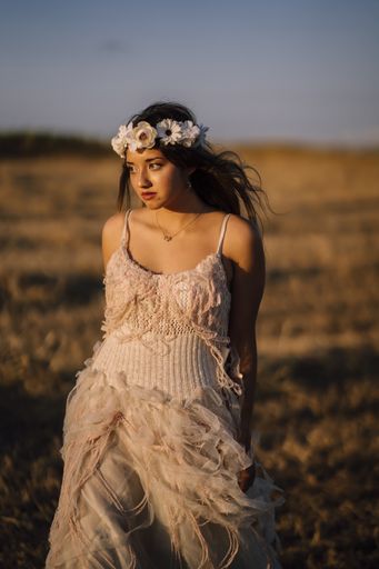 A Caucasian beautiful brunette woman wearing a white dress and white flower headband