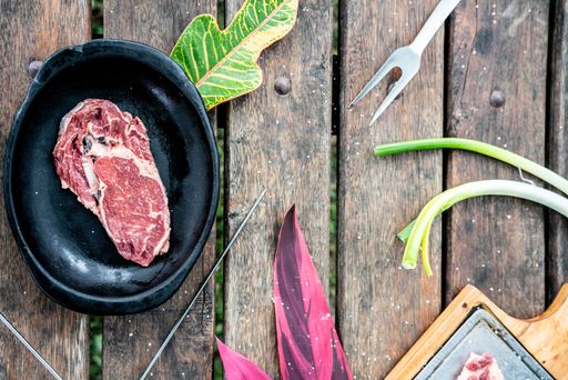 A piece of raw beef steak with herbs and spices from above