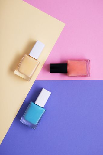 A vertical high angle shot of colorful nail polishes on a multicolor paper