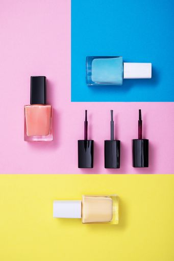 A vertical high angle shot of colorful nail polishes on a multicolor paper