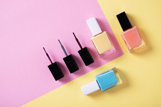 A high angle shot of colorful nail polishes on a multicolor paper