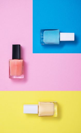 A vertical high angle shot of colorful nail polishes on a multicolor paper