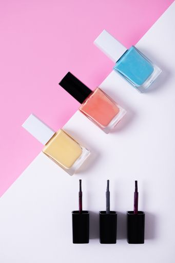 A vertical high angle shot of colorful nail polishes on a multicolor paper