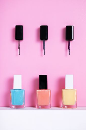 A vertical high angle shot of colorful nail polishes on a pink paper