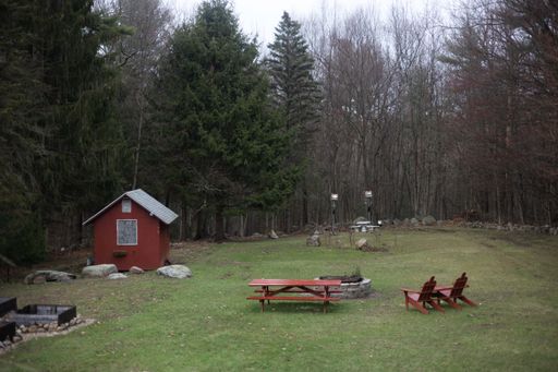 A beautiful shot of some outdoor benches near a tiny house in a forest during the day
