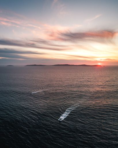 Aerial view of two boats with the Ons Island in the background at sunset, In Galicia, Spain