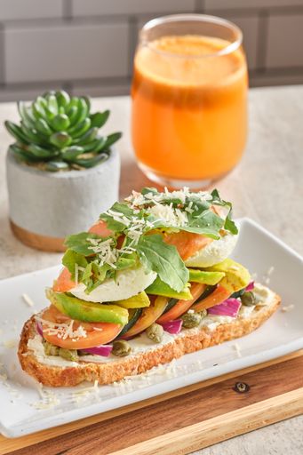 A vertical closeup shot of a bruschetta with poached eggs, avocado and tomatoes